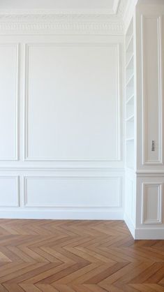 an empty room with white walls and parquet flooring in the center is shown