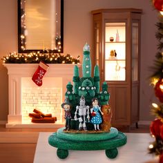 a green christmas tree with people on it in front of a fire place and fireplace