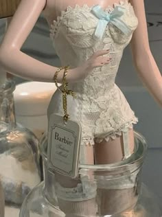 a mannequin wearing a white dress and holding a bottle in her hand with a tag on it