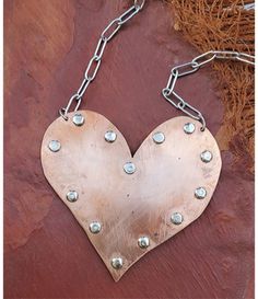 a heart shaped metal object hanging from a chain