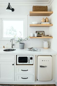 a white kitchen with open shelves and an old fashioned dishwasher in the corner