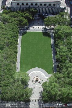 an aerial view of a large building with a lawn in the center and trees surrounding it