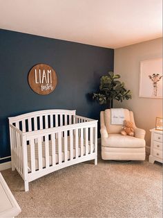 a baby's room with a white crib, chair and potted plant