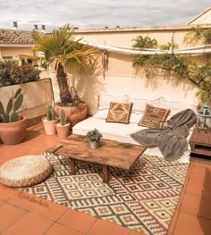 an outdoor living area with potted plants and rugs on the floor, including a couch