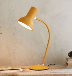 a yellow desk lamp sitting on top of a wooden table next to a pine cone