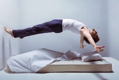 a man doing a handstand on top of a mattress