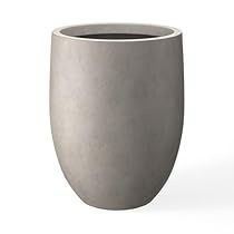 a large gray vase sitting on top of a white table next to a black cup