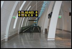 there is a sign that points in different directions at the airport terminal, and an arrow pointing to the left