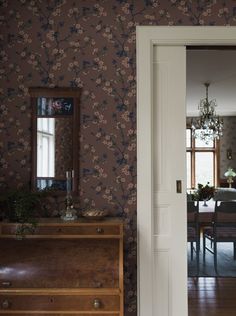 a living room with a dresser, mirror and dining room table in the back ground