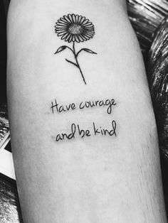 a tattoo saying have courage and be kind with a flower on the left side of the arm