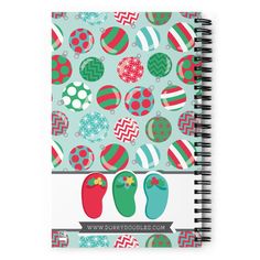 a spiral notebook with christmas ornaments and balls on the cover, which is printed in red, green, and blue