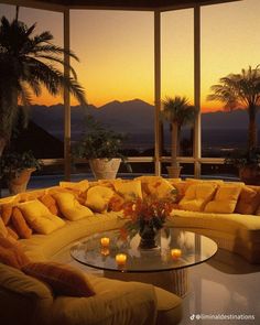 a living room filled with yellow couches next to tall windows and palm trees in the background