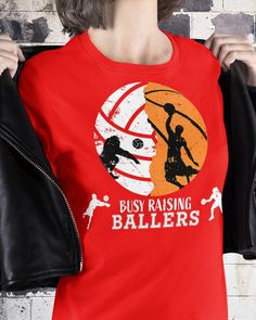 a woman wearing a red tshirt with the words busy raising ballers on it