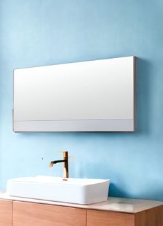 a bathroom sink sitting under a mirror next to a wall mounted faucet on a wooden cabinet