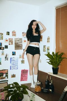 a woman standing on top of a counter next to a plant