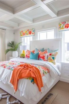 a white bed with colorful pillows and blankets on top of it in a bright bedroom