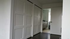 an empty room with white doors and wood floors