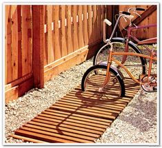 a bike parked next to a wooden fence in front of a gated area with gravel