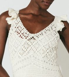 a woman wearing a white crochet top with ruffles