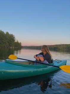 a woman sitting in a green kayak on the water