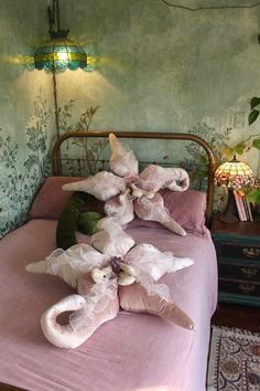 a bed with pink sheets and pillows on it in front of a wallpapered room