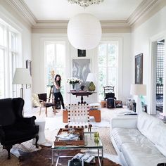 a woman standing in the middle of a living room filled with furniture and decor items