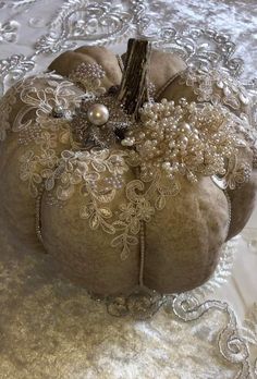 a decorative pumpkin sitting on top of a white tablecloth covered table cloth with beads and pearls