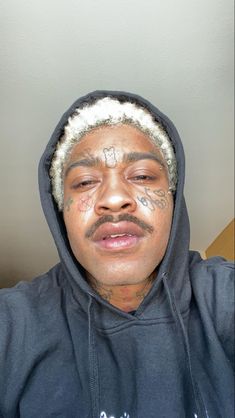 a man with tattoos on his face wearing a hoodie