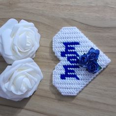 two crocheted hair clips with white roses on the top and one blue flower on the bottom