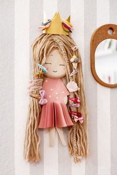 a paper doll with long blonde hair and a crown on her head is next to a mirror