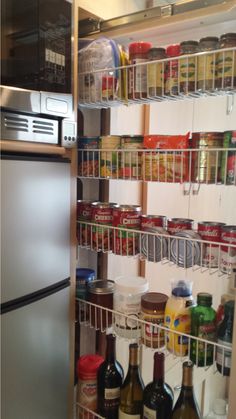 an organized pantry with wine, food and condiments on the bottom shelf is shown