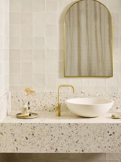 a bathroom sink with a gold faucet and mirror above it