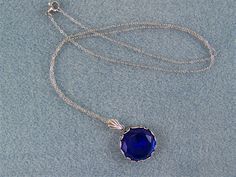 "This faceted dark blue sapphire is set in a round floral designed bezel frame. A fan shaped bail holds this deep blue gem on an oxidized silver cable link chain, closed with a lobster claw clasp. The 18mm (3/4\") Czech glass gem is dark blue and has many facets that reflect the light. The chain in 20\" in length. Chain length can be ordered from 16\" up to a 24\" with no additional cost. Just message me with your request at time of purchase. This lovely sparkling cobalt blue necklace would enha Faceted Round Sapphire Jewelry, Blue Faceted Jewelry For Formal Occasions, Blue Round Cabochon Jewelry, Victorian Blue Gemstone Necklace, Round Sapphire Cabochon Necklaces, Round Sapphire Cabochon Necklace, Victorian Sapphire Round Jewelry, Blue Round Faceted Jewelry, Blue Faceted Round Jewelry