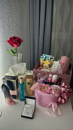 an assortment of personal care items on a table next to a vase with a rose in it