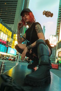 a woman with red hair and tattoos sitting on top of a skateboard in the city