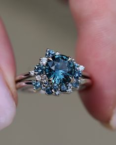 a woman's hand holding a blue and white diamond ring