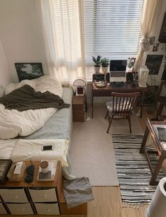 a bedroom with a bed, desk and chair in it next to a large window