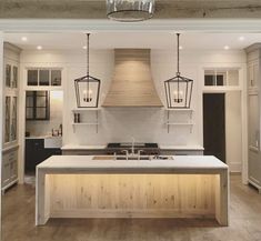 a large kitchen with an island and two pendant lights hanging from it's ceiling