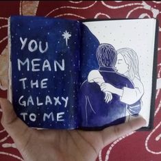 a hand holding an open book with the words you mean the galaxy to me