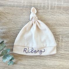 Wrap your little one in personalized comfort with our Hand Embroidered Baby Hat, custom stitched with your baby's name. Made from soft, breathable cotton, this unique newborn beanie is the perfect baby shower gift and a cherished keepsake. Each hat is carefully hand embroidered, ensuring a one-of-a-kind touch. Ideal for newborns and infants, this personalized baby hat combines style and sentiment, making it a must-have for any new parent. Soft Cotton Cap, Adjustable Soft Hat For Gifts, Adjustable Soft Hat As A Gift, Soft Adjustable Hat As A Gift, Cotton Hat, One Size Fits Most, Adjustable Cotton Bonnet As Gift, Embroidered Baby Hat, Baby Knot Hat, Personalized Baby Hat