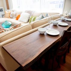 a living room filled with furniture and a wooden table topped with white plates on top of it