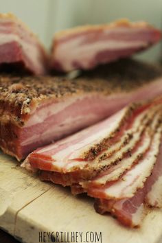 sliced ham sitting on top of a cutting board next to another piece of meat with seasoning