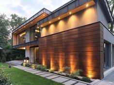 a modern house is lit up at night with lights on the windows and side walls