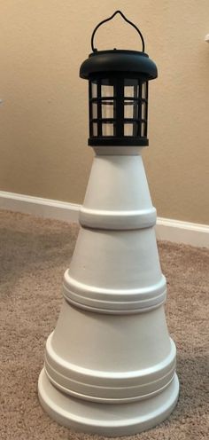 a white lighthouse with a black top on carpeted floor next to wall and door