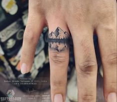 a person's hand with a small tattoo on it and mountains in the background