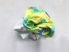 a yellow and green flowered cloth on top of a white surface with blue flowers