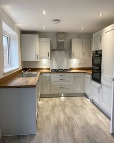 an empty kitchen with white cabinets and wood counter tops, along with stainless steel appliances