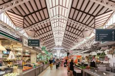 the inside of a grocery store filled with lots of fresh produce and people walking around