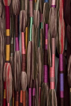 many different colored spools of thread hanging on a wall