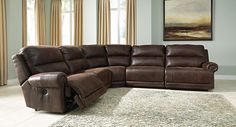 a large sectional couch in a living room with two windows and rug on the floor